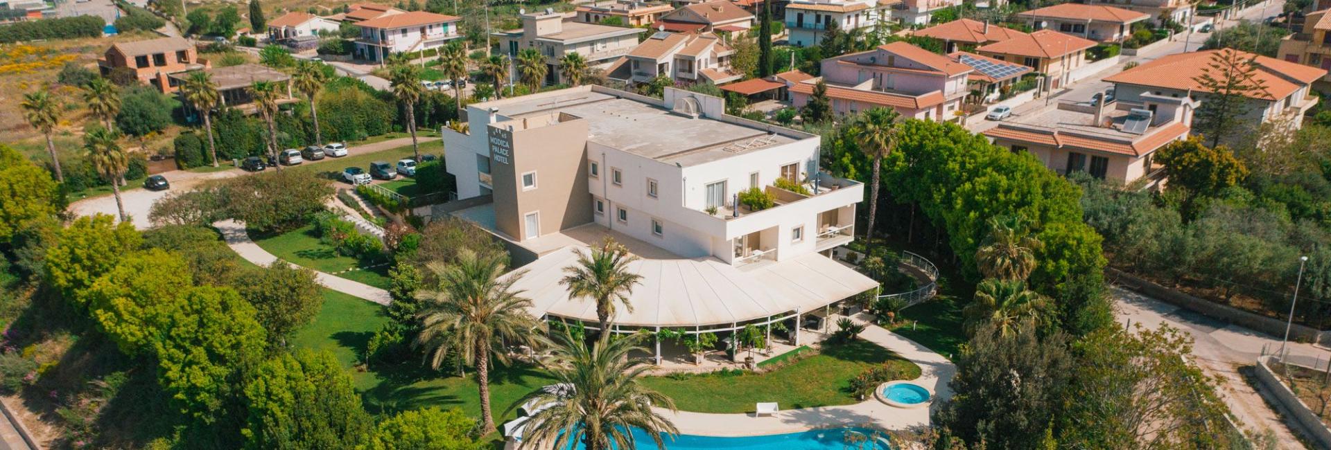 Hotel moderno con piscina, giardino e vista panoramica su una zona residenziale.