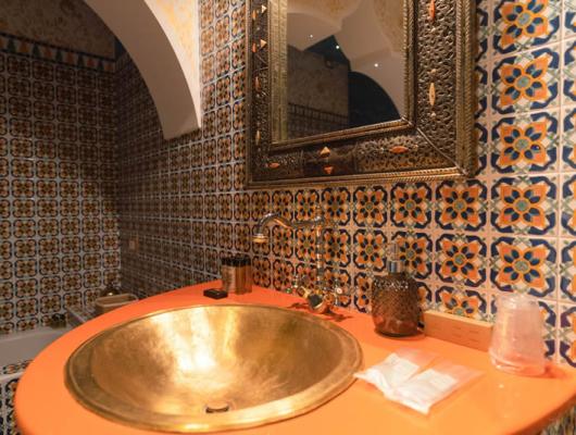 Colorful bathroom with a golden sink and decorative tiles.