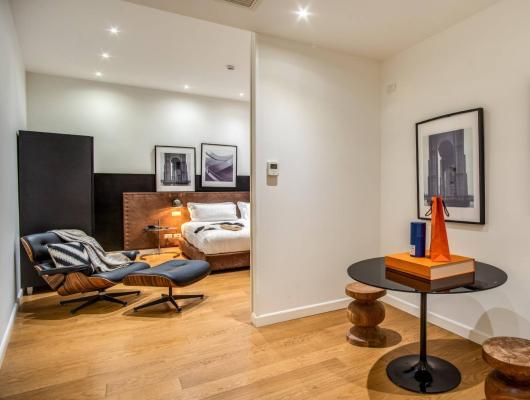 Modern room with bed, chair, table, and artwork on the walls.