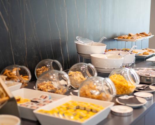 Buffet with cereals, pastries, and bread in a modern setting.