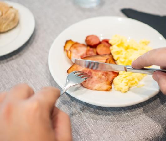 Colazione con uova strapazzate, pancetta e salsicce.