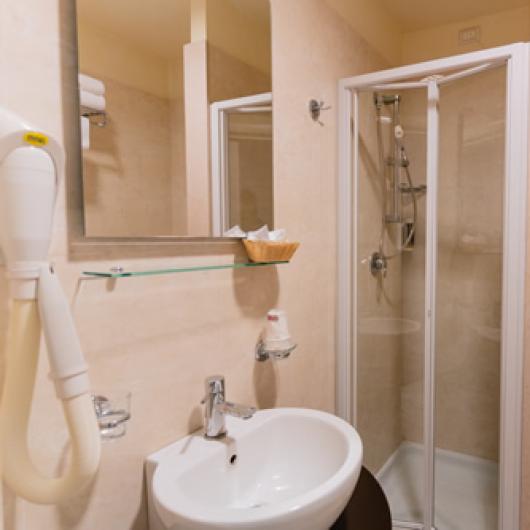 Bathroom with shower, sink, mirror, and hairdryer.