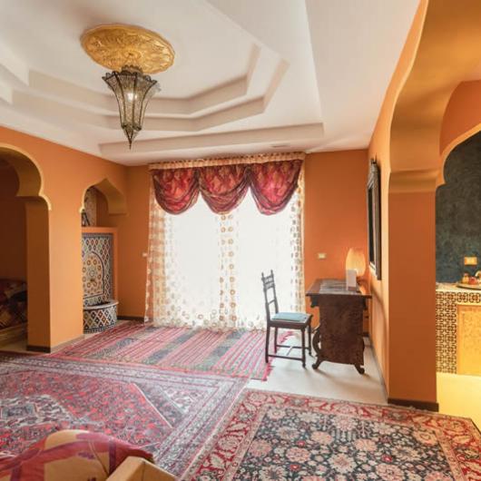 Elegante stanza con arredi marocchini, tappeti colorati e illuminazione decorativa.