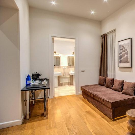 Modern living room with brown sofa and round table, bathroom in the background.