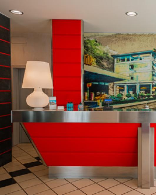 Modern reception with red counter and mural of a historic building.