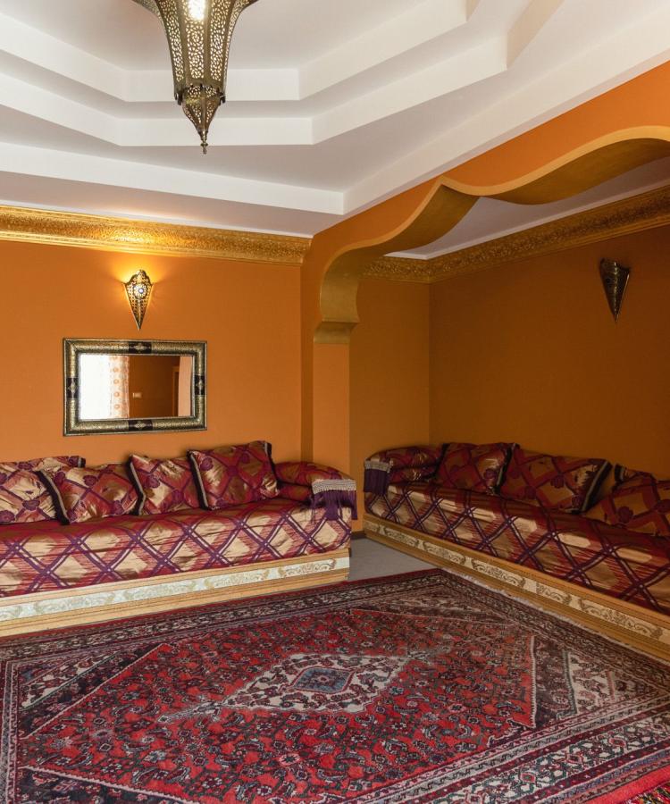 Salotto arabo con divani colorati, tappeti e decorazioni dorate.